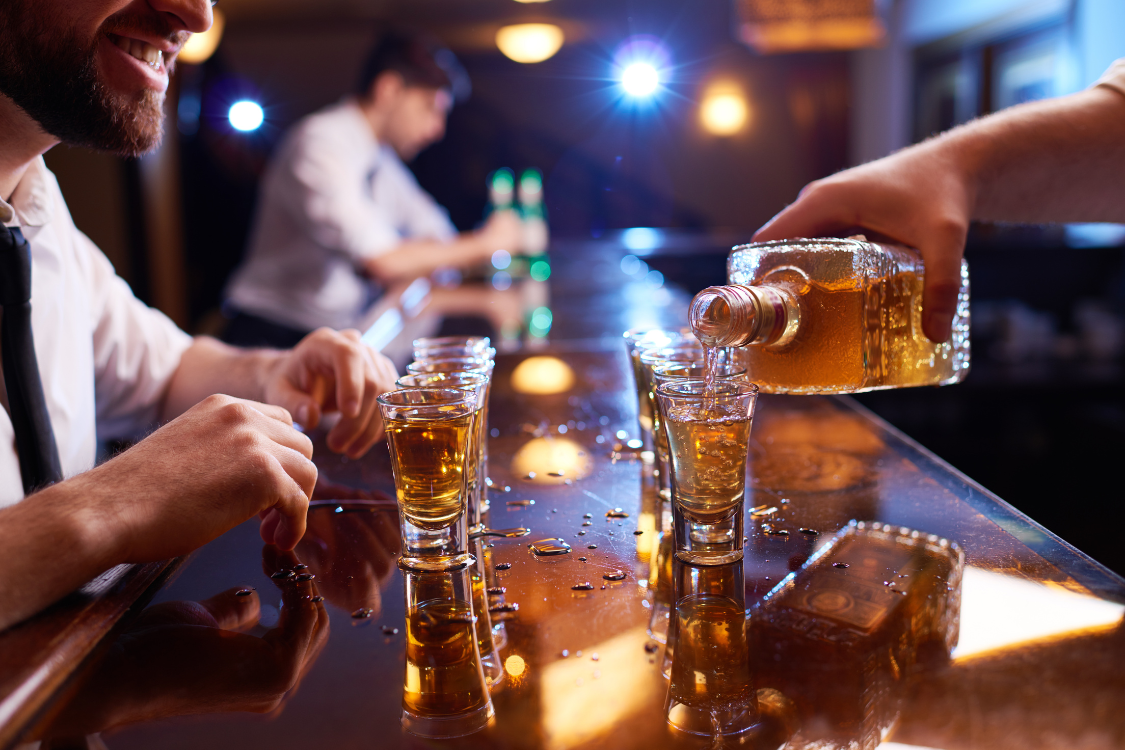 People taking shots of alcohol at a bar, representing alcohol consumption and how it can lead to dehydration before using electrolyte drinks for recovery.