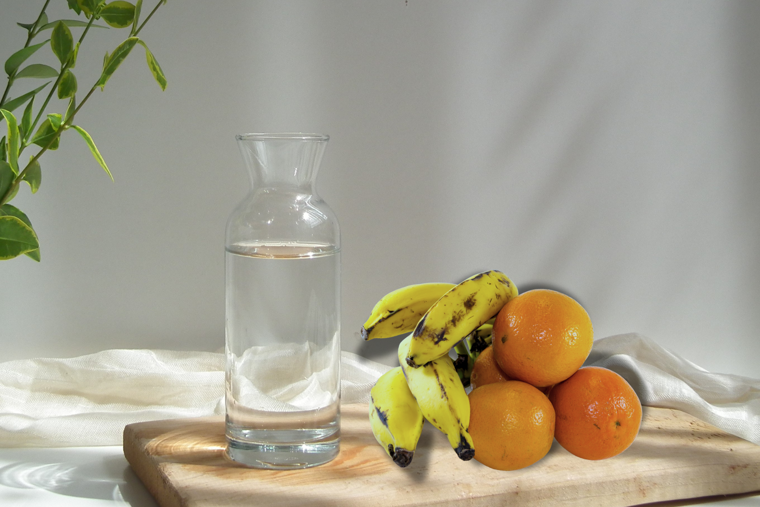 Small pitcher of water with oranges and banana beside it