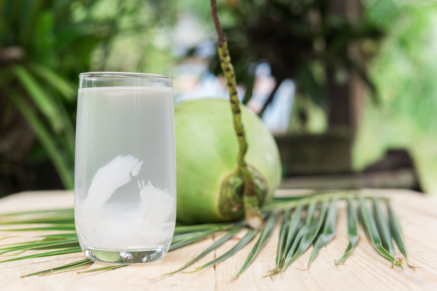 Glass of coconut water in a tropical setting.