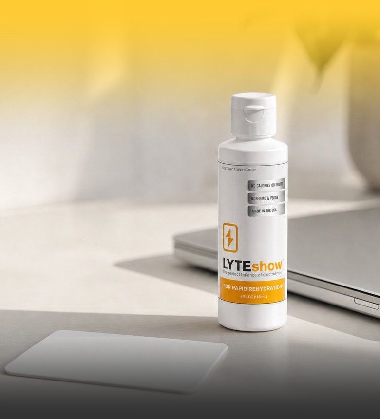 A LyteShow bottle on a desk beside a laptop