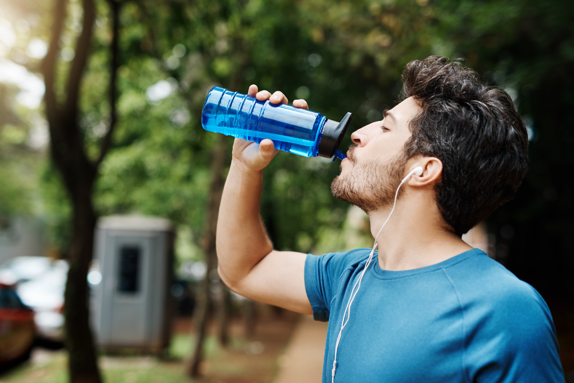 Athlete rehydrating with an electrolyte drink outdoors.