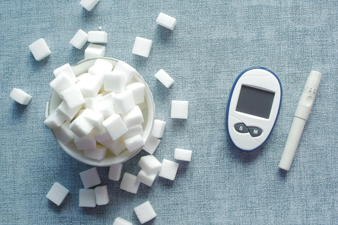 Blood sugar monitor beside sugar cubes, symbolizing blood glucose control and the role of electrolytes for diabetics.