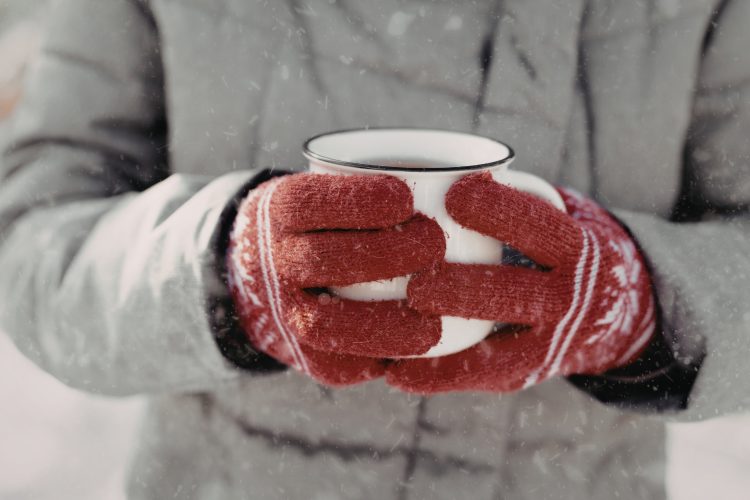 A person holding a cup of coffee in the snow
