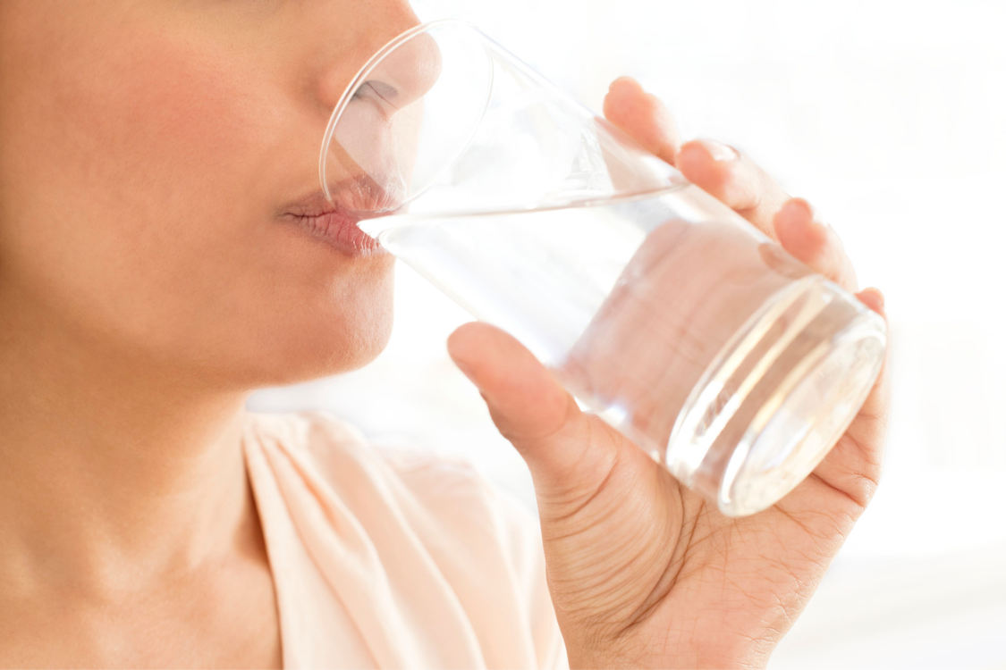 Woman drinking water to support electrolytes and hydration balance in daily life.
