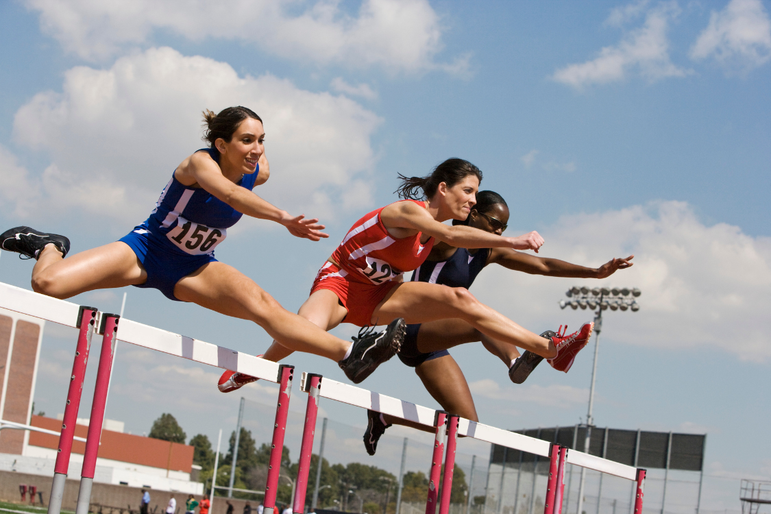 Athletes competing in a high-intensity hurdle race, where significant sweat loss requires electrolyte drinks.